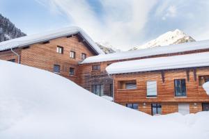 een gebouw bedekt met sneeuw met bergen op de achtergrond bij Appart Gastauer in Sankt Gallenkirch