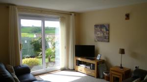 a living room with a television and a large window at Sunny detached bungalow, Nr Looe in Saint Keyne