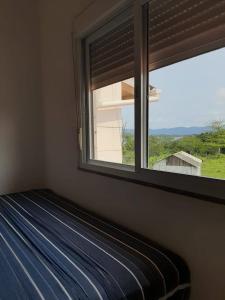 um quarto com uma janela e uma cama com um cobertor azul em Cantinho da Barra em Imbituba
