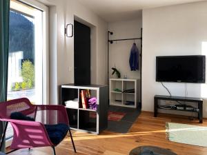 a living room with a flat screen tv and pink chairs at Traumblick Dachstein in Radstadt