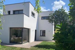 een wit huis met grote glazen deuren bij Maison Joli Soir à Ambleteuse in Ambleteuse