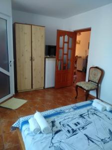 a bedroom with a bed and a chair and a kitchen at Casa Carlo in Eforie Nord