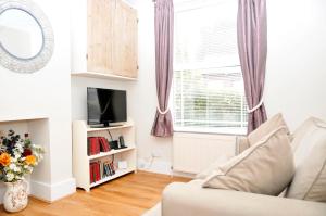 a living room with a couch and a tv and a window at Little Lane in Alverstoke