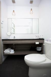 La salle de bains est pourvue de toilettes blanches et d'un grand miroir. dans l'établissement Motel Blanche d'Haberville, à Saint-Jean-Port-Joli