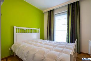 a bedroom with a white bed with a green wall at Zeppelin 0102 in Koksijde