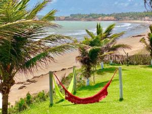 una hamaca en una playa con palmeras y el océano en Casa Paraiso en Maxaranguape