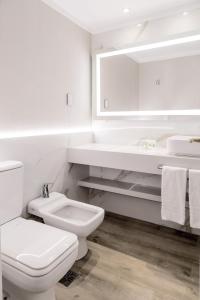a white bathroom with a toilet and a sink at Holiday Inn Rosario, an IHG Hotel in Rosario