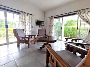 ein Wohnzimmer mit Stühlen, einem Tisch und Fenstern in der Unterkunft CHEZ MARVA Grande Villa COCO 3 à 12 personnes in La Digue