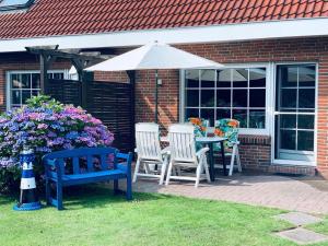 eine Terrasse mit Tisch und Stühlen und einem Sonnenschirm in der Unterkunft 50059 Ferienhaus in Altfunnixsiel