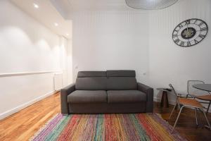 a living room with a couch and a clock on the wall at Large Flat At 2 Steps From The Eiffel Tower in Paris