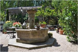 a stone fountain in a garden with potted plants at La Figuiere Fontaine de Vaucluse in Fontaine-de-Vaucluse