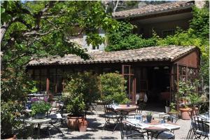 a patio with tables and chairs and a building at La Figuiere Fontaine de Vaucluse in Fontaine-de-Vaucluse