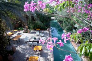 a pool with tables and chairs and purple flowers at Dar al Hossoun in Taroudant