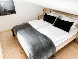 a bedroom with a bed with white sheets and black pillows at Fewo Aschauer in Schönau am Königssee