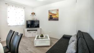 uma sala de estar com um sofá e uma televisão em Apartments Bepo em Rogoznica