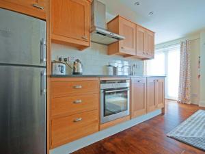 a kitchen with wooden cabinets and a stainless steel refrigerator at No 1 The Hinges in Newquay