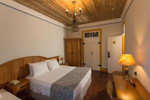 une chambre avec un lit, une table et une lampe dans l'établissement Pousada Solar da Ópera, à Ouro Preto
