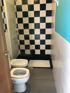 a bathroom with a toilet and a black and white checkered wall at Departamento en Villa Allende in Villa Allende +3 photos