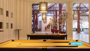 Vila Galé Resort Touros - All Inclusive في توروس: صف من طاولات البلياردو في غرفة مع أشخاص في الخلفية