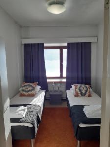 2 letti in una camera con tende viola di Kuukkeli Apartments Sodankylä a Sodankylä