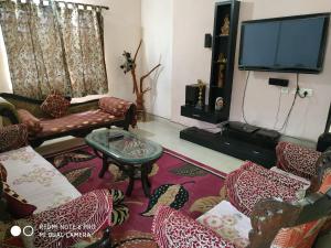ein Wohnzimmer mit Sofas und einem Flachbild-TV in der Unterkunft Tranquil Hospitality in Bhubaneshwar