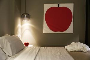 a bed with a red apple painting on the wall at Neko Boutique Hotel in Cagliari
