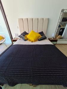 a black and white bed with a yellow pillow on it at Departamento costado mall plaza, Balmaceda Antofagasta in Antofagasta