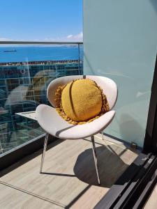 a white chair with a yellow pillow on a balcony at Departamento costado mall plaza, Balmaceda Antofagasta in Antofagasta