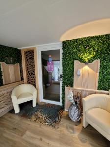 a living room with two white chairs and a green wall at Ambiente Hotel garni in Plauen