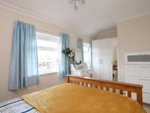 a bedroom with a bed with blue curtains and a window at Eirlys in Caernarfon +10 photos