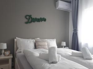 a white bed with white sheets and a sign on the wall at Angel Residence in Sibiu