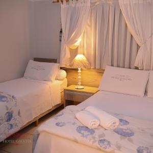 a room with two beds and a table with a lamp at Hotel Gaucha in Guaíra