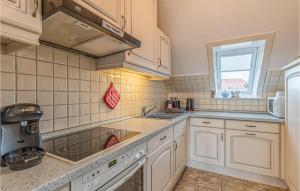 a kitchen with white cabinets and a sink and a window at Amazing Apartment In Friedrichskoog With Kitchen in Friedrichskoog-Spitz