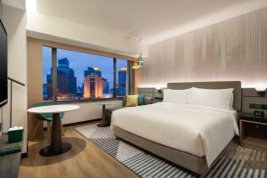 a hotel room with a bed and a large window at Holiday Inn Shanghai Nanjing Road by IHG in Shanghai