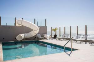 a pool with a slide on the side of a building at Pinamar Beach Resort in Pinamar