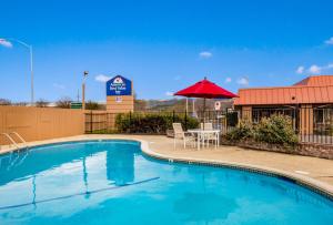 uma piscina com uma mesa e um guarda-sol vermelho em Americas Best Value Inn - Ukiah em Ukiah