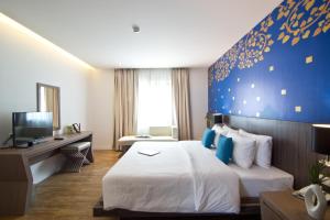 Habitación de hotel con cama y pared azul en Tevan Jomtien Pattaya en Jomtien Beach