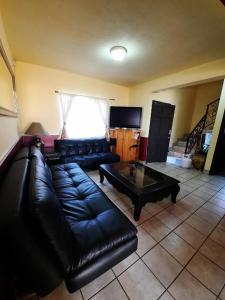 a living room with a black leather couch and a coffee table at Terraza de campo in Rosarito