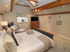 1 dormitorio con 1 cama blanca grande y 1 sofá en The Coach House Apartment, en Tewkesbury