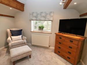 sala de estar con TV de pantalla plana y silla en The Coach House Apartment en Tewkesbury