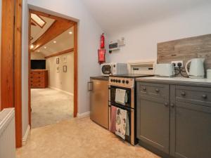 a kitchen with a stove top oven next to a hallway at The Coach House Apartment in Tewkesbury