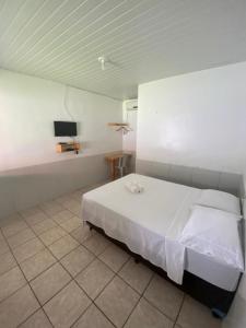 a bedroom with a bed and a tv on a wall at Pousada Andorinhas in Santo Amaro