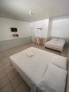 a large room with two beds and a tv at Pousada Andorinhas in Santo Amaro