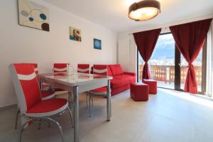 a living room with a red couch and a table and chairs at Stars & Mountain Apartment in Buşteni
