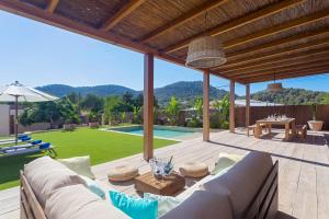 eine Terrasse mit einem Sofa, einem Tisch und einem Pool in der Unterkunft Villa Can Ginebra in San Jose de sa Talaia