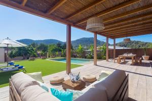 a patio with a couch and a table and a pool at Villa Can Ginebra in Sant Josep de Sa Talaia