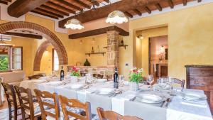 een eetkamer met een lange tafel met witte borden en stoelen bij Il Casale Di Manuele 12, Emma Villas in Montepulciano