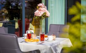 a table with a vase of flowers and food on it at Hotel Urban in Plovdiv +65 photos