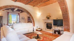 Una sala de estar con sofás blancos y una chimenea. en Il Fitto 10, Emma Villas, en Cortona