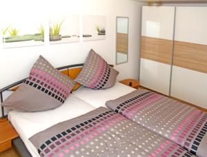 Schlafzimmer mit einem Bett mit rosa und grauen Kissen in der Unterkunft Haus Tannenweg in Zell an der Mosel